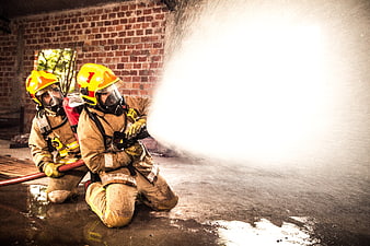 Two Firefighters Kneeling With Water Hose During Training