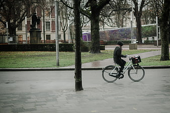 Cyclist riding white bike on wet city street