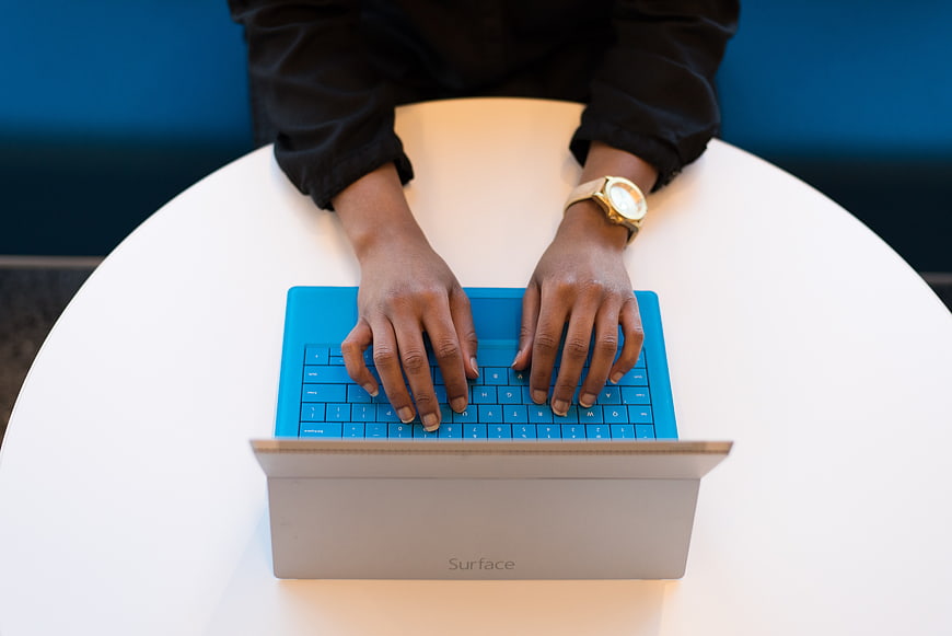 Hands Typing on Blue Surface Laptop Keyboard