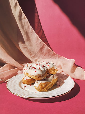 Glazed Eclairs with Raspberries on Pink Background