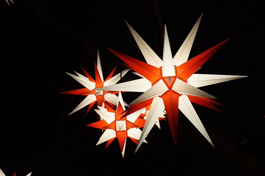 Illuminated red and white Christmas star lanterns against black background