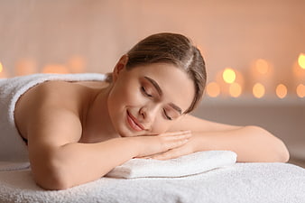 Relaxed woman lying on massage table with candles