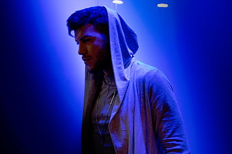 Young man in hoodie under dramatic blue lighting