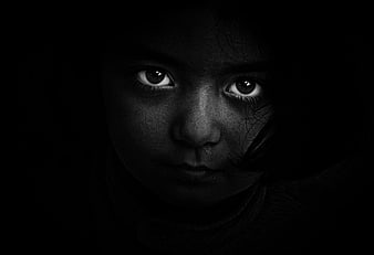 Dramatic black and white portrait of a child's eyes in darkness