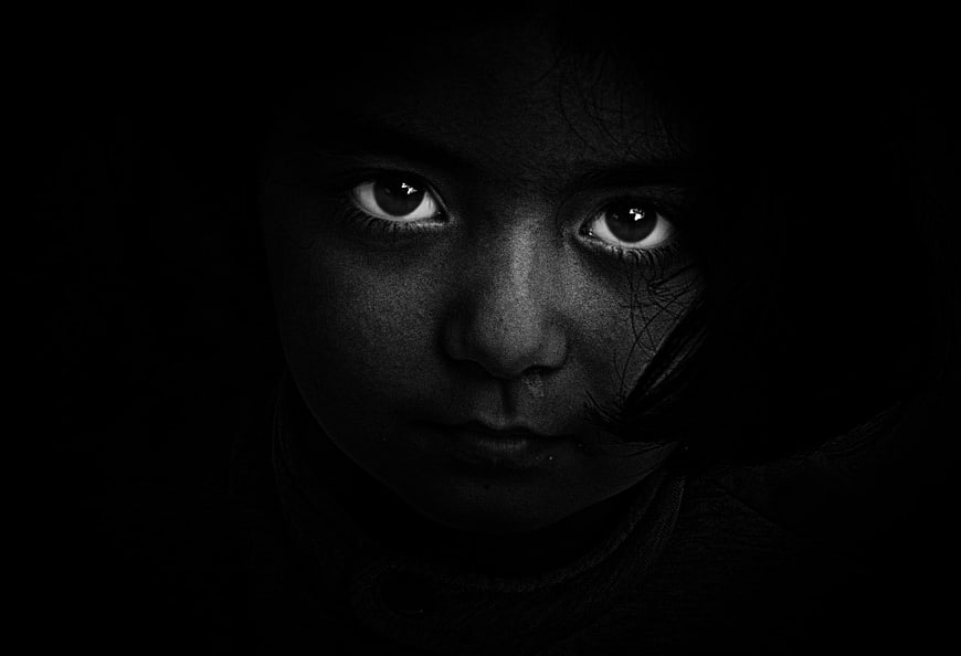 Dramatic black and white portrait of a child's eyes in darkness