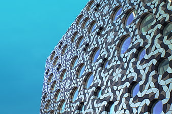 Modern geometric building facade with round windows against blue sky