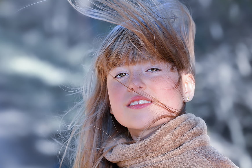 Portrait of young girl with windblown hair outdoors