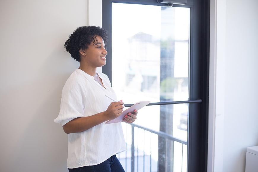 Confident Black Woman Using Tablet by Window