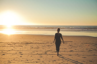 Woman Walking on Sandy Beach at Golden Sunset