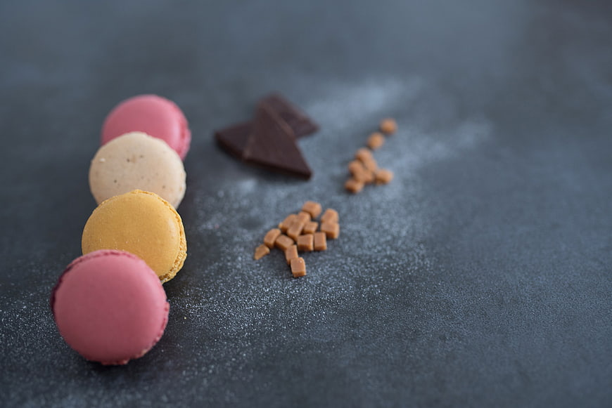 Colorful Macarons and Chocolate on Dark Slate Background
