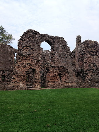 Ancient stone castle ruins with archway on green lawn
