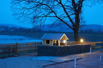 Cozy wooden cabin by lake at blue hour with warm lights