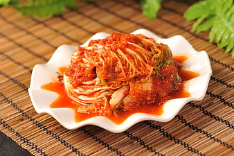 Spicy Kimchi on White Plate with Bamboo Mat Background