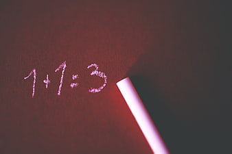 Chalk writing 1+1=3 on red textured background