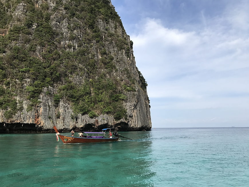 Longtail boat near limestone cliffs in tropical turquoise sea
