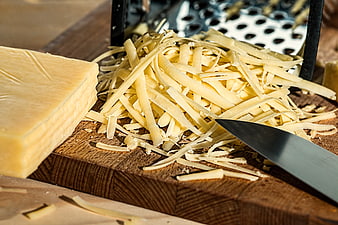 Freshly Grated Cheese On Wooden Board With Grater And Knife