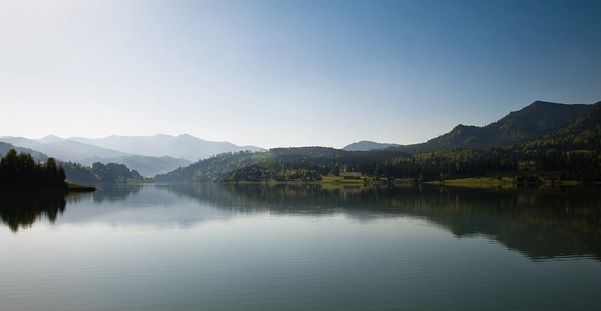 Serene Mountain Lake with Forest Reflections and Misty Peaks