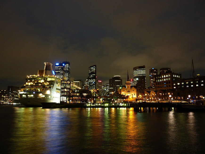 Sydney skyline at night with cruise ship and harbor reflections