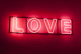 Red neon love sign on textured wall