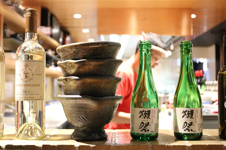 Sake and wine bottles with stacked ceramic bowls in restaurant