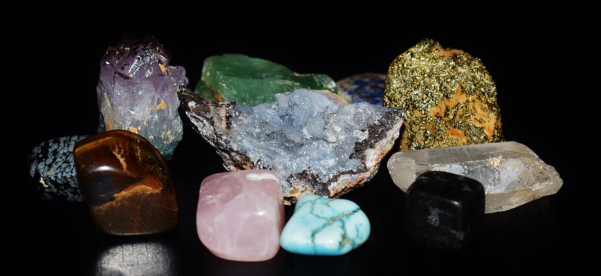 Collection of colorful raw gemstones and crystals on black background
