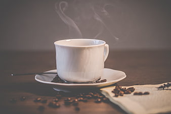 Steaming White Coffee Cup with Beans on Wooden Table