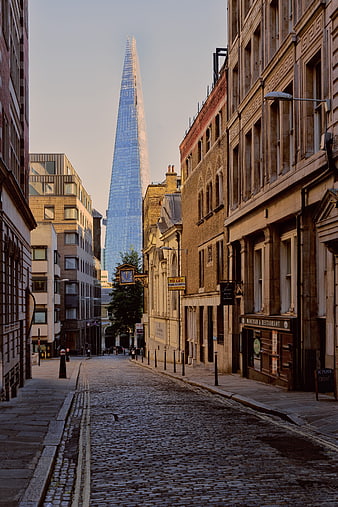 The Shard Tower Rising Above Historic London Cobblestone Street