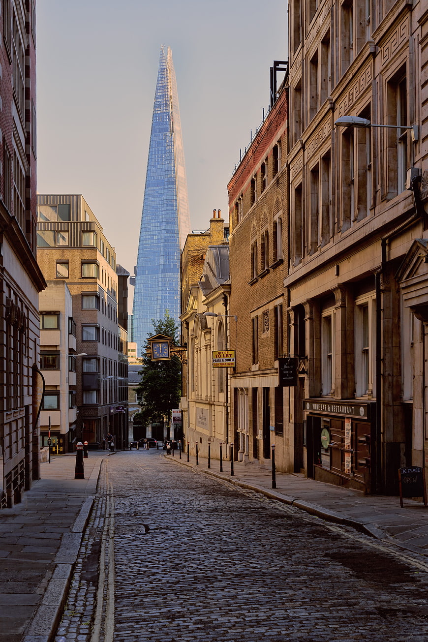 The Shard Tower Rising Above Historic London Cobblestone Street