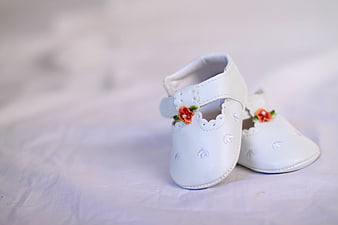 White Baby Shoes With Floral Embellishments On Soft Background