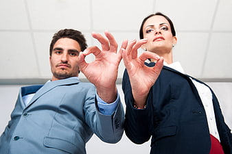 Businessman and Businesswoman Making OK Gesture in Office