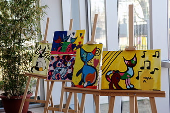 Colorful cat paintings on easels in art gallery