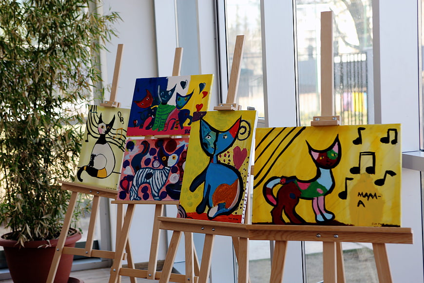 Colorful cat paintings on easels in art gallery