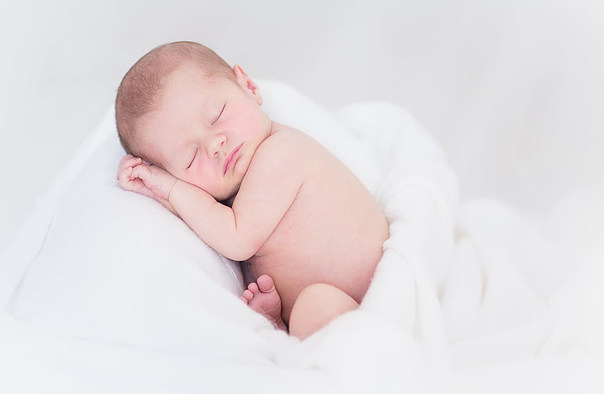 Sleeping newborn baby wrapped in white blanket