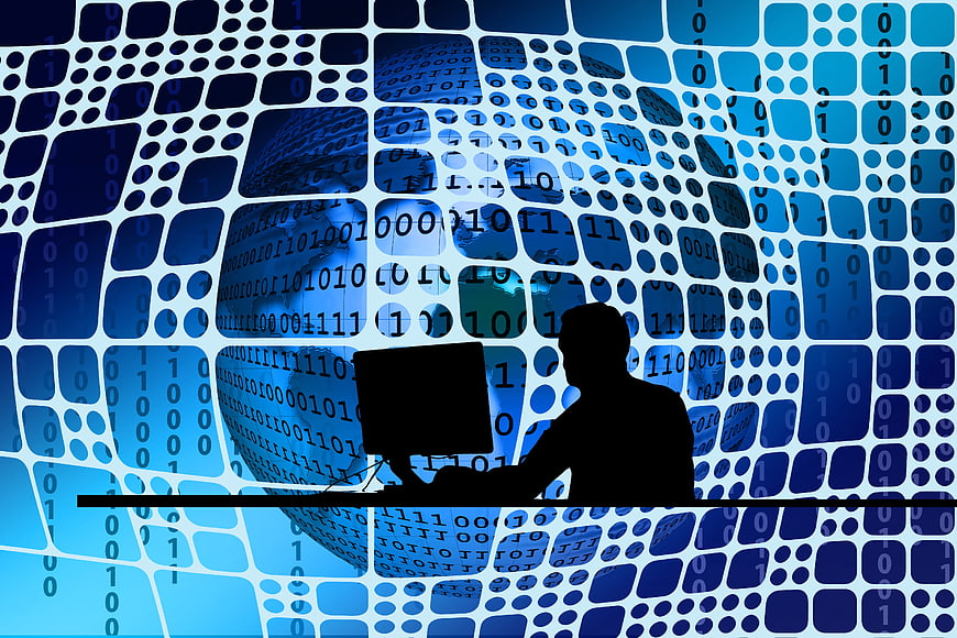 Silhouette of person working at computer with digital network background