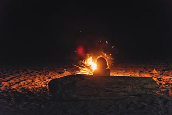Woman Silhouette Sitting By Campfire On Beach At Night