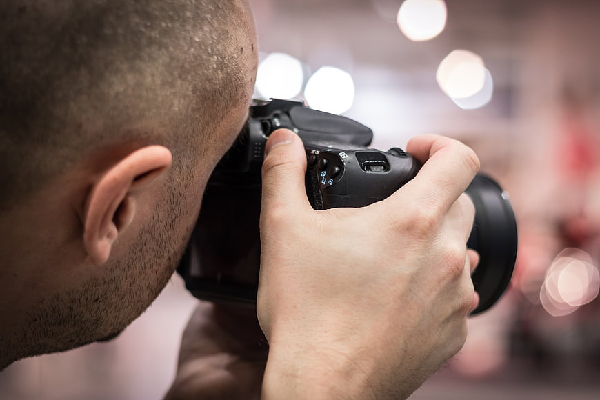 Photographer Holding DSLR Camera Close Up With Bokeh Background
