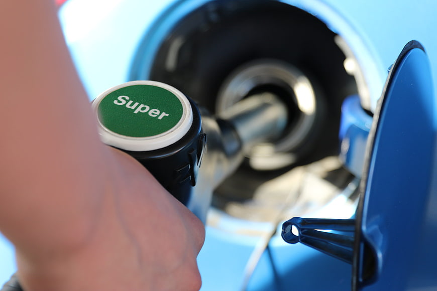 Hand holding Super fuel nozzle refueling blue car