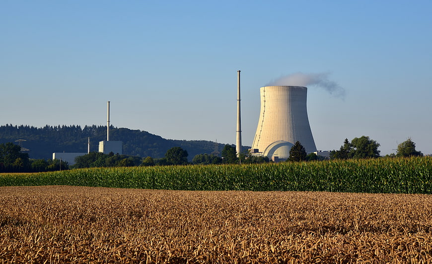 Nuclear power plant cooling tower rising above green agricultural fields