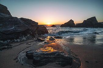 Golden Sunset Over Rocky Coastal Beach with Ocean Waves