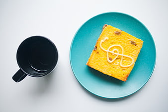 Overhead view of coffee mug and bread with cream on teal plate
