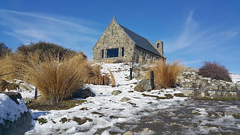 Stone Church on Snowy Hillside Under Blue Sky