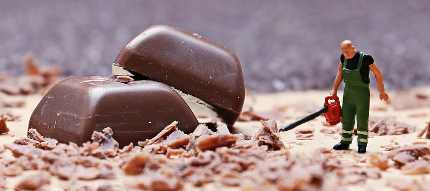Miniature Worker Cleaning Chocolate Shavings With Leaf Blower