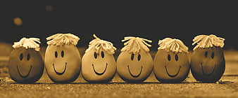 Row of six smiling anti-stress balls with yarn hair on a textured surface