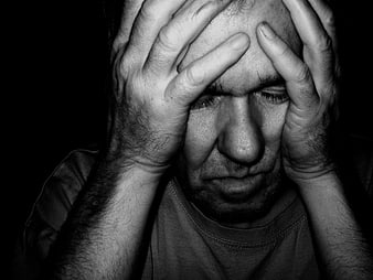 Close-up of distressed man holding head in hands