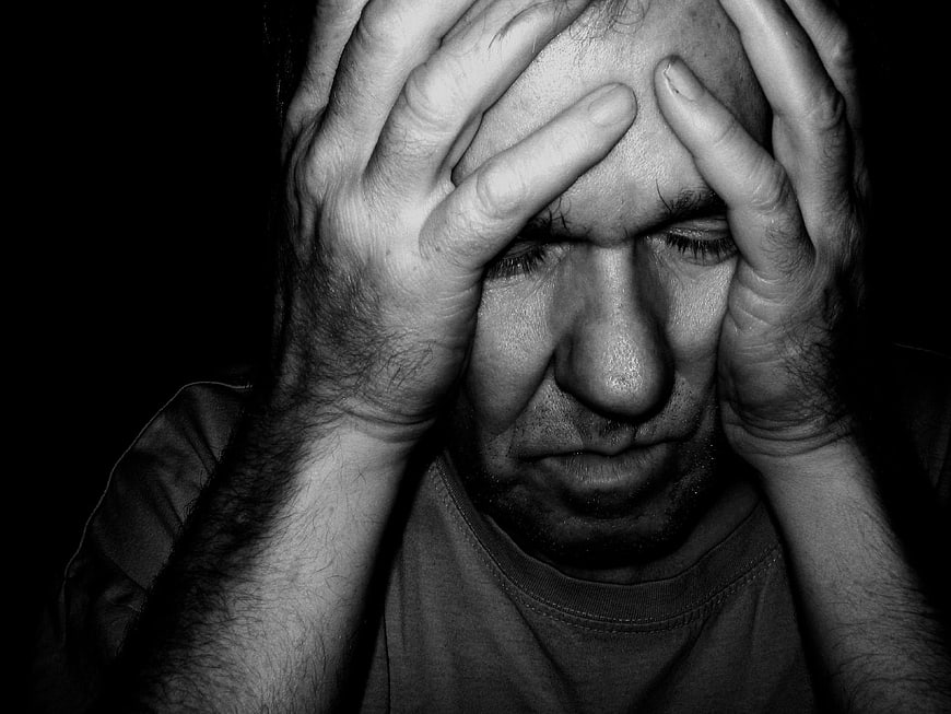 Close-up of distressed man holding head in hands