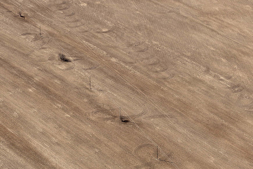 Aerial view of dry agricultural field with tractor tracks