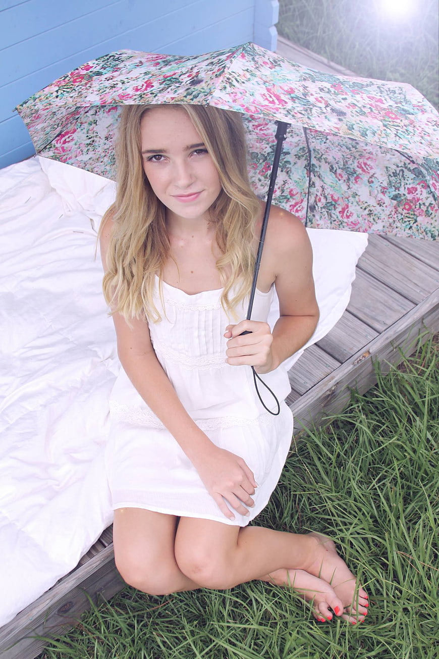 Blonde Woman Sitting with Floral Umbrella on Wooden Deck