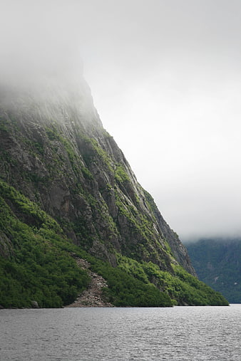 Misty Mountain Cliff Over Calm Fjord Water