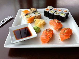 Assorted sushi platter with salmon nigiri and rolls on white plate