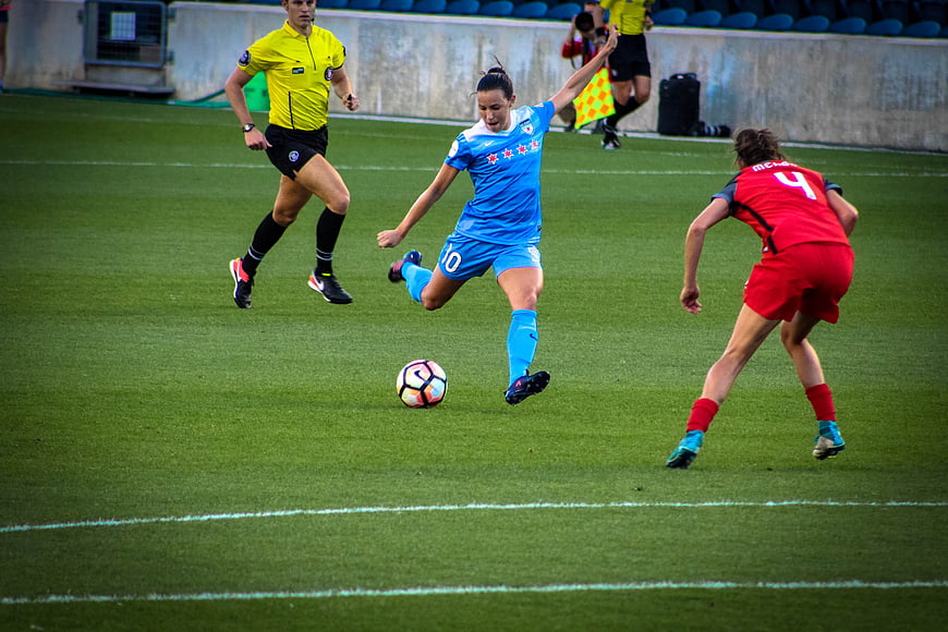 Women's soccer match action shot with player kicking ball